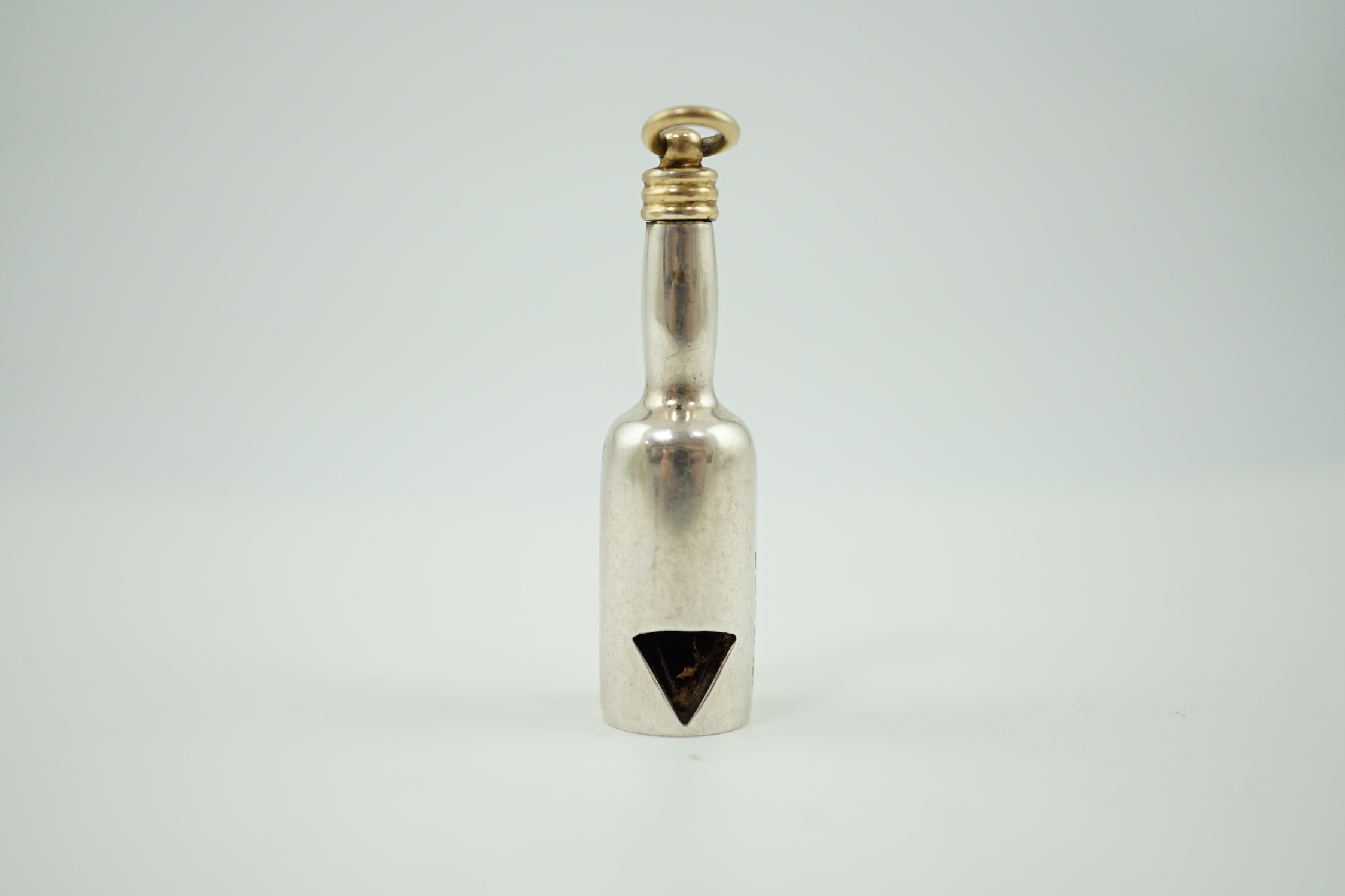 A late Victorian novelty parcel gilt silver cigar cutter, modelled as a bottle, the hinged section enamelled with a head of a dog